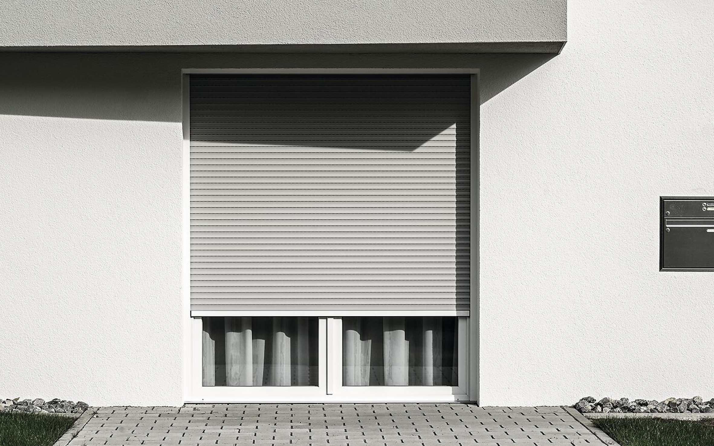 Terrassentür mit halb heruntergelassenen Rollladen mit grauen Lamellen